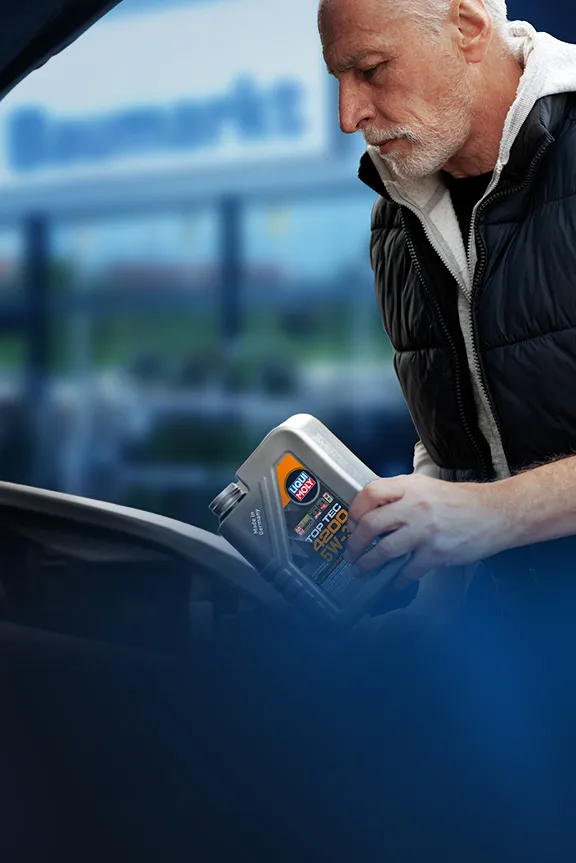 Mann füllt Liqui-Moly-Motoröl in den Motorraum eines Autos mit geöffneter Motorhaube.