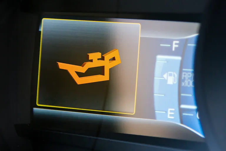 Gelb leuchtendes Ölkanne-Symbol als Warnanzeige auf einem digitalen Fahrzeug-Display.